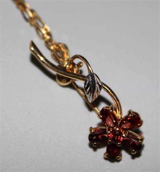 A 9ct gold and garnet flower brooch, on an 18ct gold chain, brooch 1.25in.